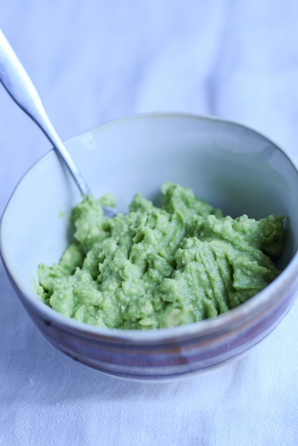 A small bowl with mashed avocado in it