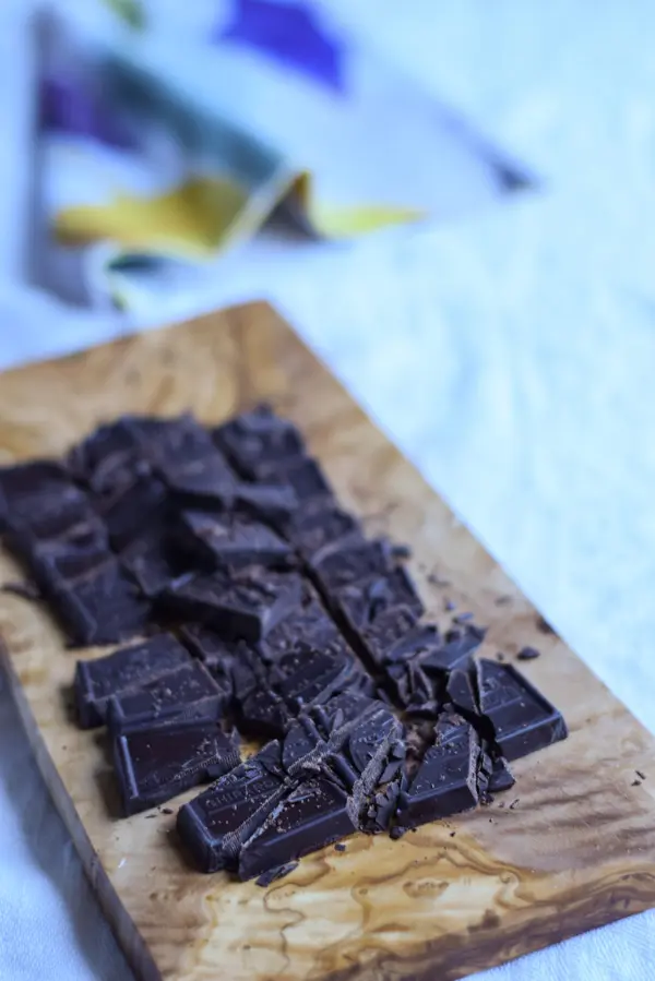 A wooden board with chopped up chocolate on it