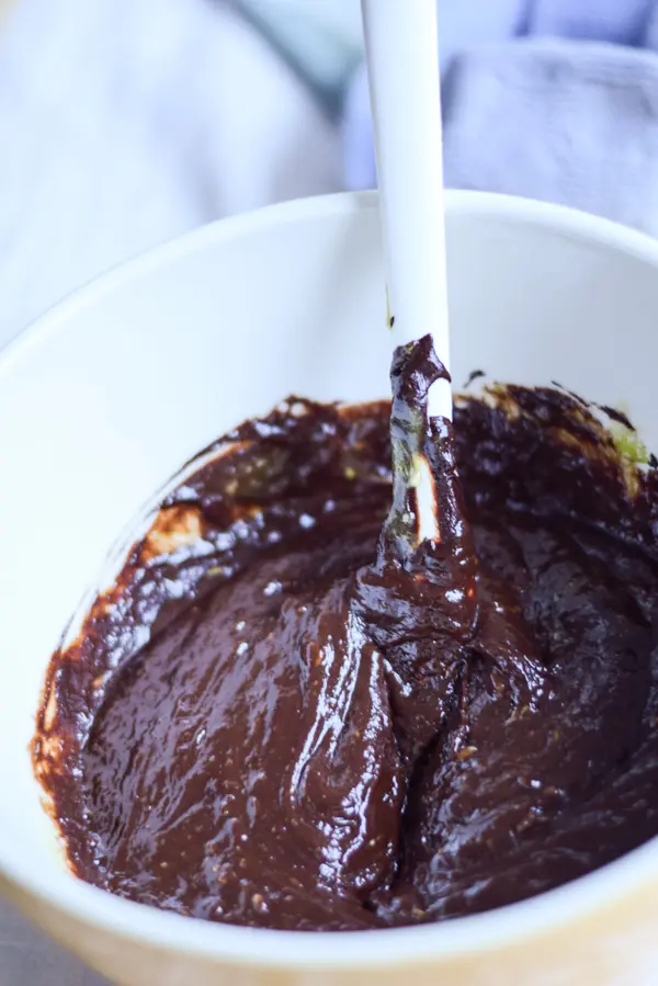 Melted chocolate and avocado in a bowl with a spatula in it