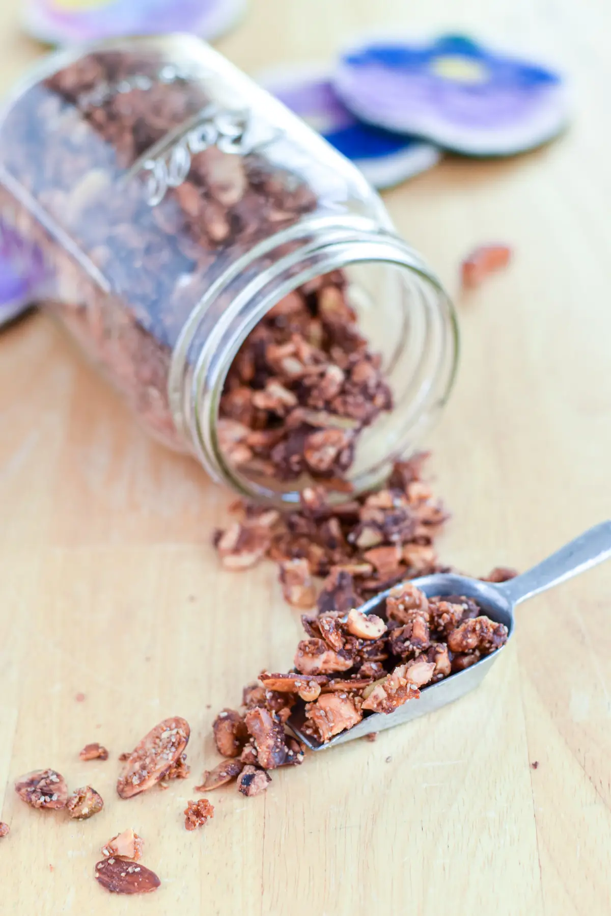 A scoop with granola spilling off it with a jar on it's side behind it