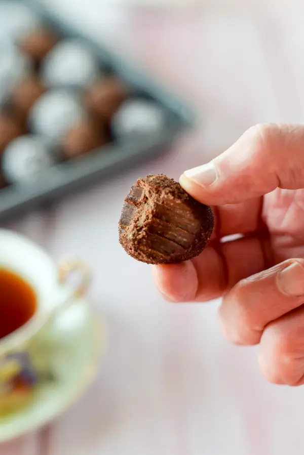 A male hand holding one of the  rum balls that has a bite taken out of it