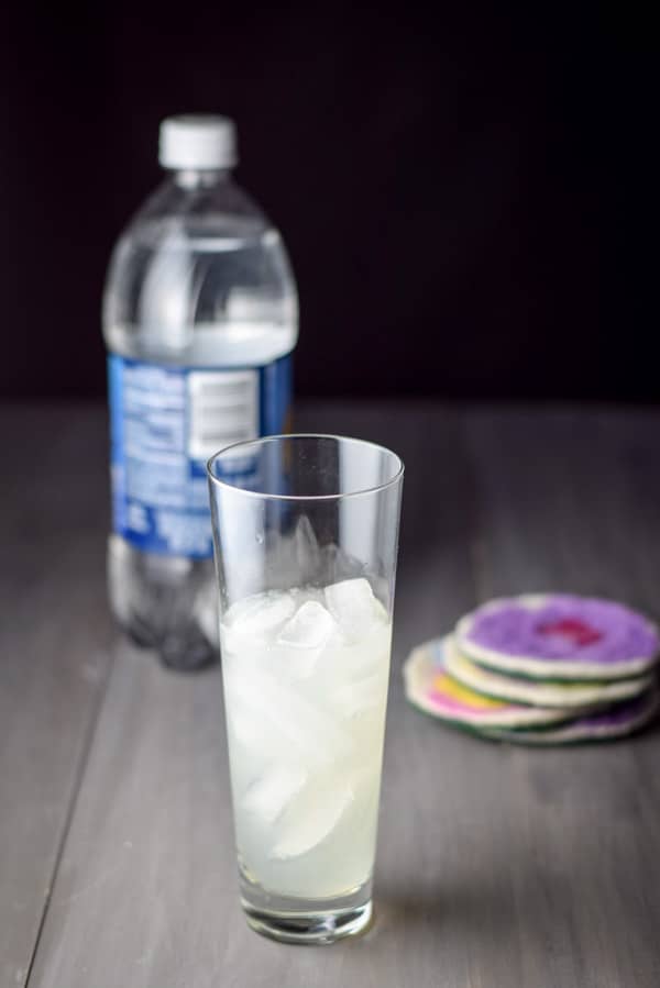The contents of the shaker poured into the glass with club soda in the background