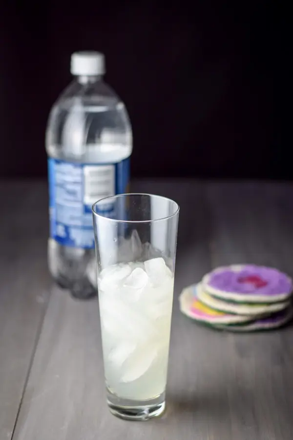 The contents of the shaker poured into the glass with club soda in the background