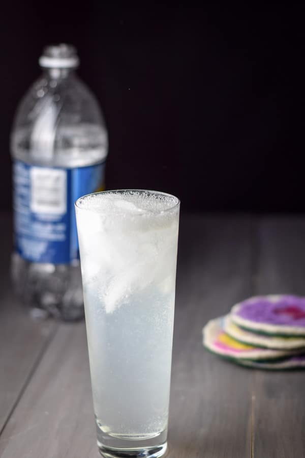 Club soda poured into the flared tall glass with club soda in the background