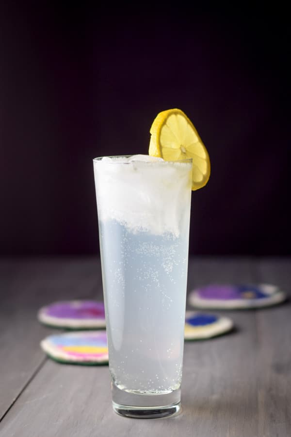 Vertical view of the cloudy cocktail in a flared glass with lemon as the garnish