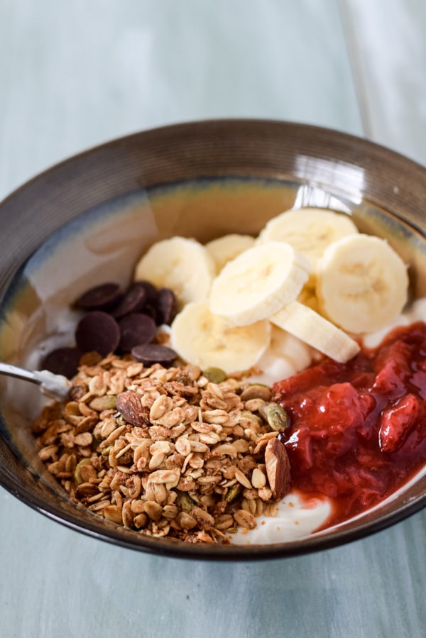 Strawberry sauce on the yogurt with granola, bananas and chocolate bits
