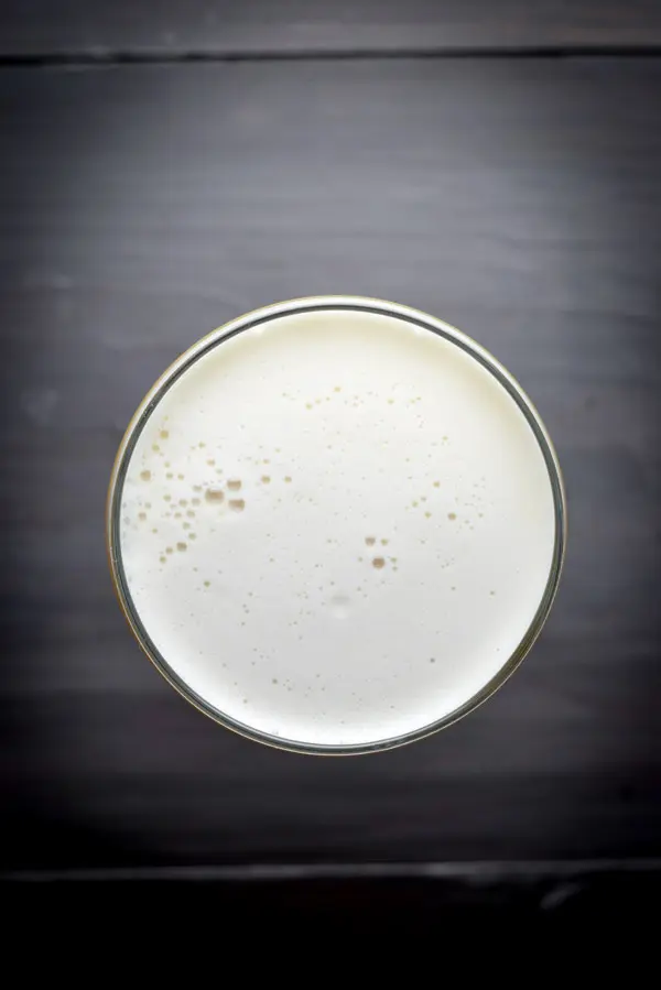 Overhead view of a foamy cocktail on a grey table
