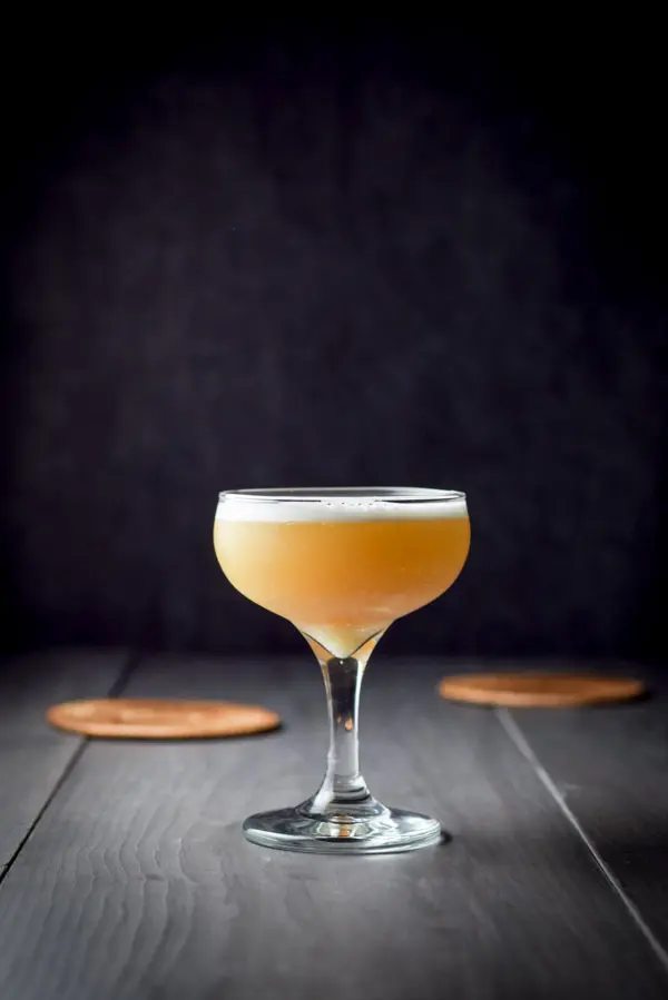 The amber cocktail with a foam head in vertical view