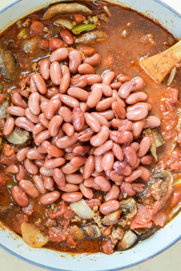 Kidney beans added to the chili in a Dutch oven