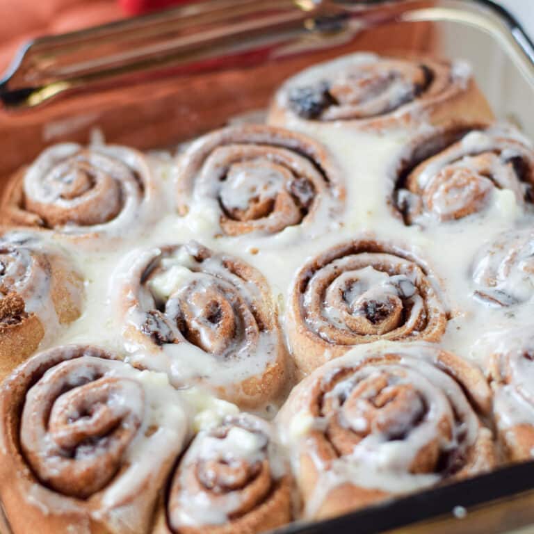 A pan of glazed cinnamon rolls in a glass pan - square