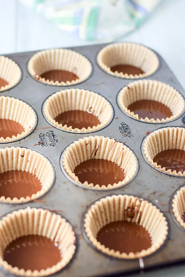 First layer of melted chocolate in baking cups in the muffin pan