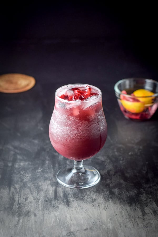fruit added red wine sangria with a small glass bowl of it in the background