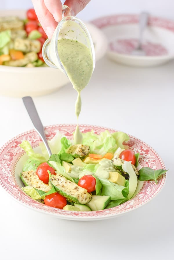 Drips of green dressing going on the salad