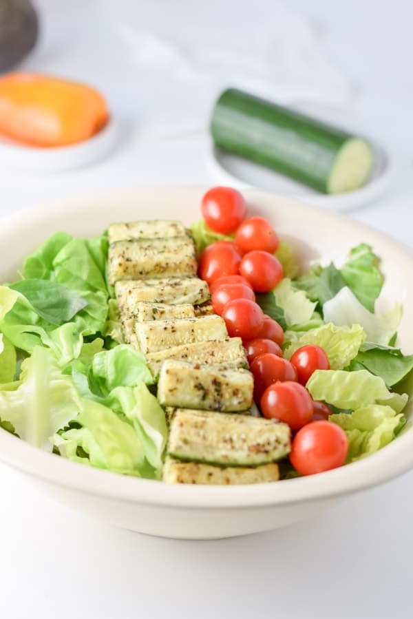 Grape tomatoes lined up next to the zucchini and more veggies in the background