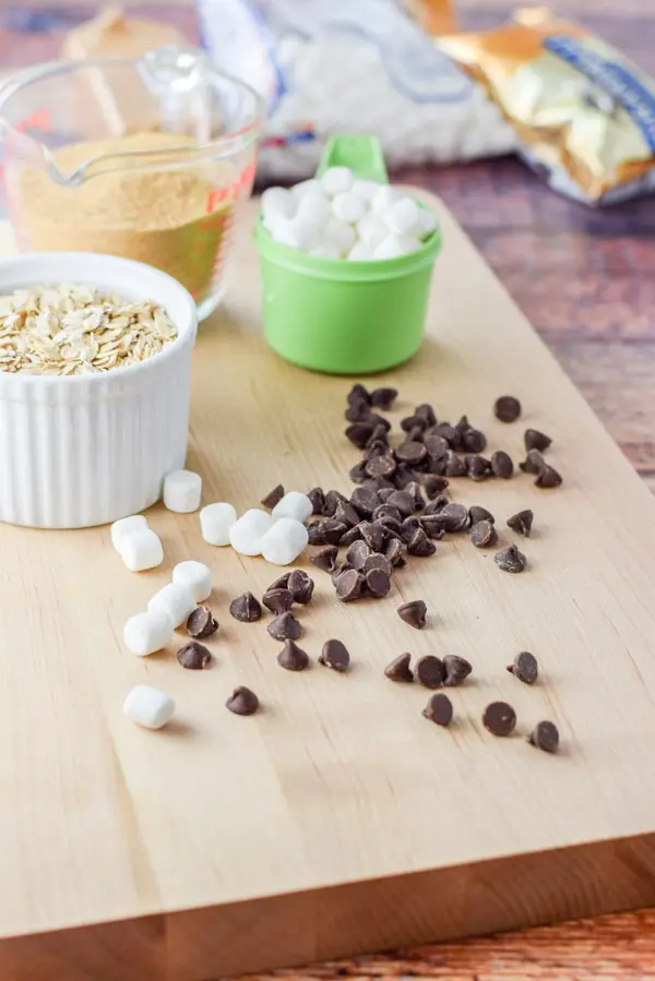 Oats, graham cracker crumbs, marshmallows and chocolate bits on a wooden board