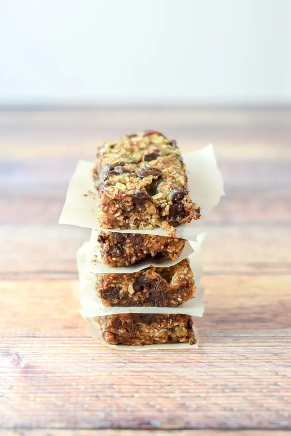 Four chocolate chip granola bars stacked on top of each other with parchment paper between them