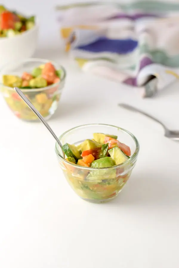 A few clear bowls with the avocado mixture in it and a very colorful napkin in the background