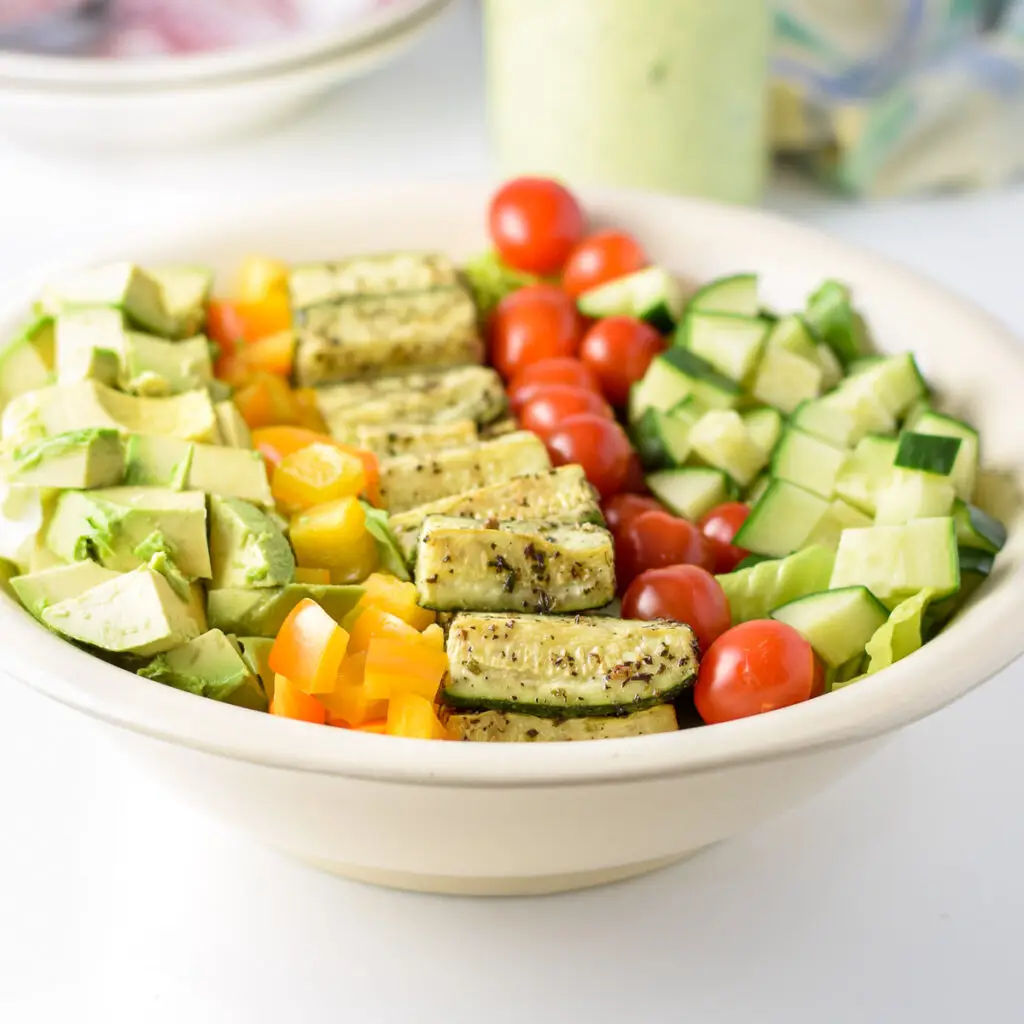 A bowl with lots of vegetables on the salad - square
