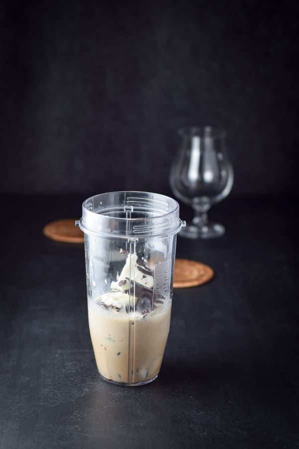The yogurt bars added to the blender container with the tulip glass in the background