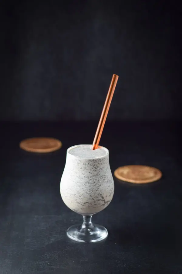 A straw sticking out of a tulip glass filled with the frozen drink