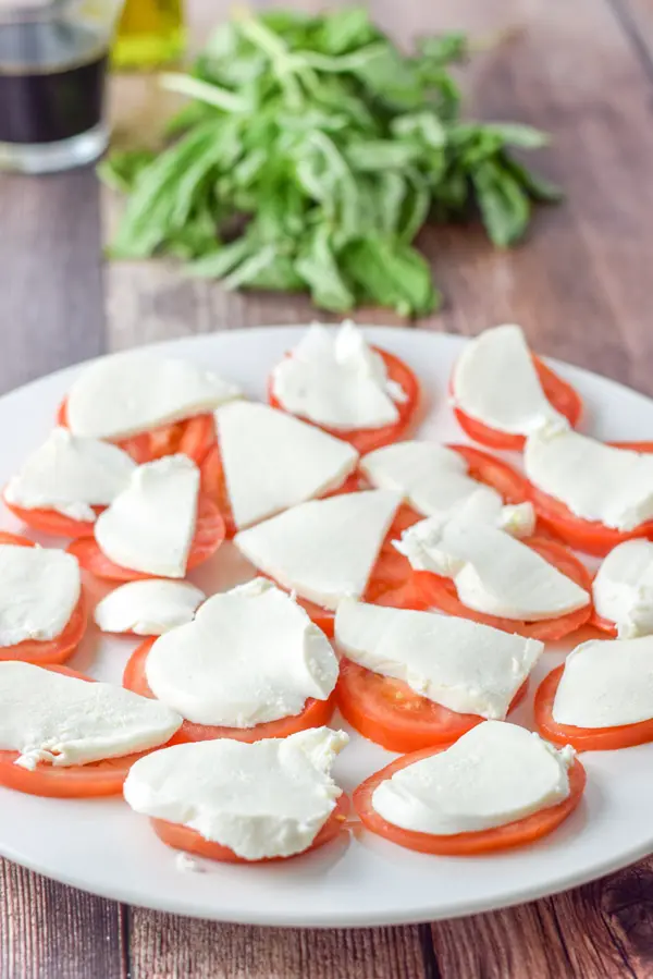 Cheese slices on tomatoes with basil, vinegar and oil in the background