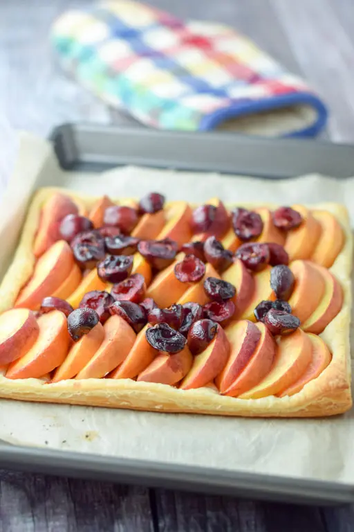 Fluffy pastry with peaches and cherries on a pan
