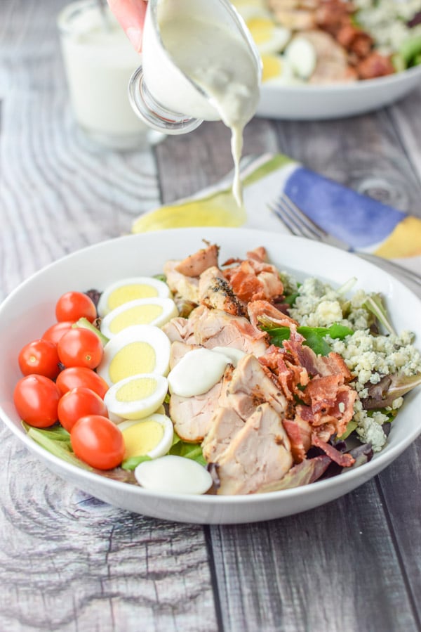 More dressing being poured on the salad - there are drips from the little pitcher