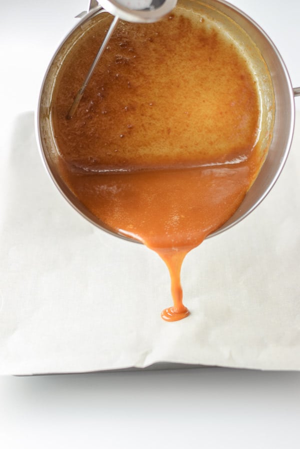 A pan dribbling caramel sauce on parchment paper