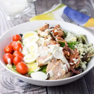 Blue cheese dressing fully poured onto the colorful lined salad with dressing in a container