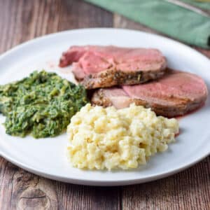 A plate of mashed root with spinach and slices of lamb - square