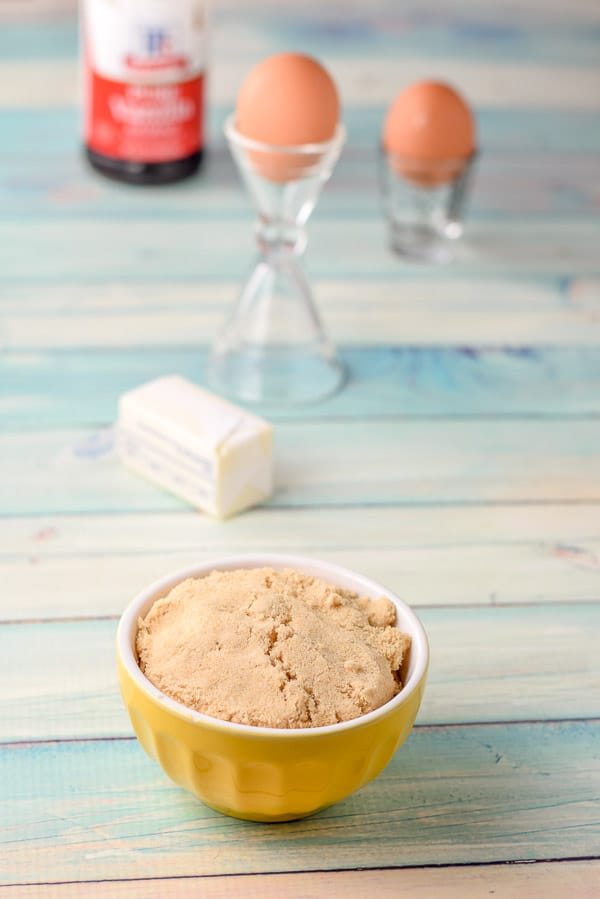Brown sugar, butter, eggs and vanilla on a green table