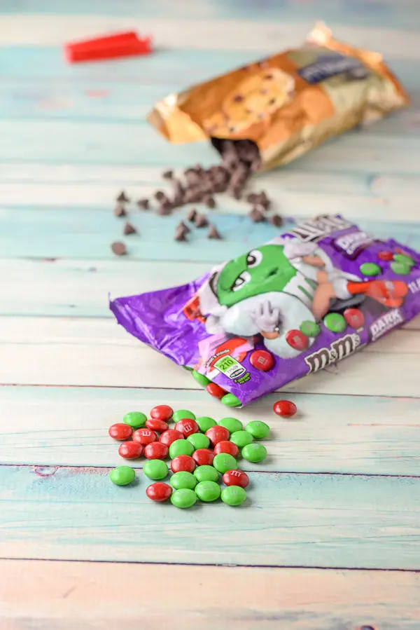 M & M's and chocolate chips strewn on the table with the bags near them