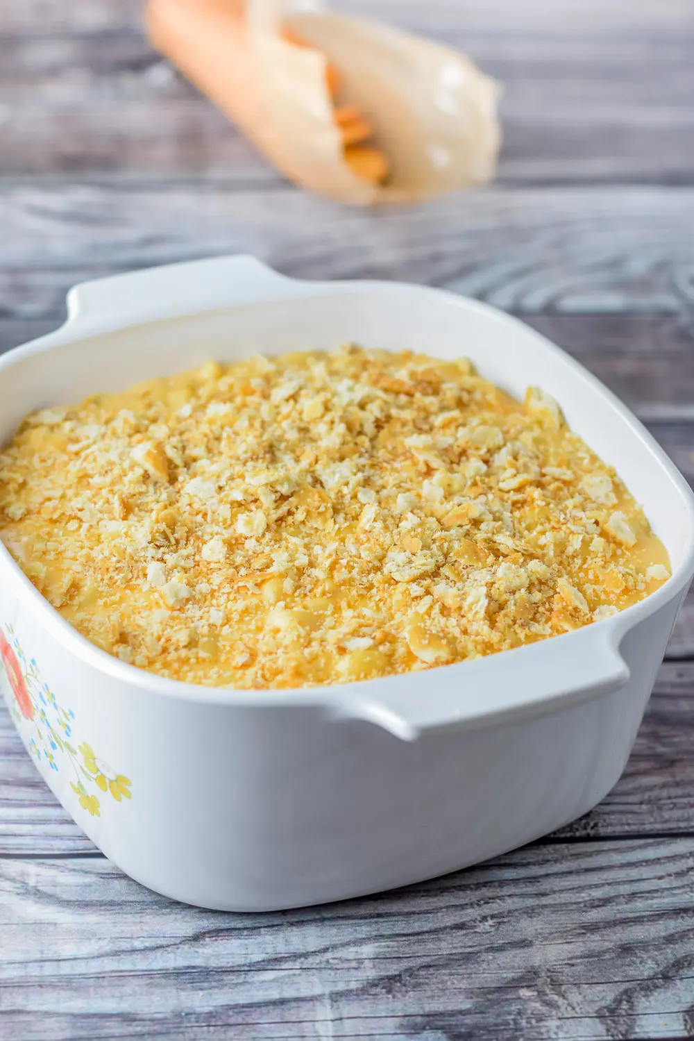 Ritz crackers crumbled on cheese sauce and macaroni in the baking dish