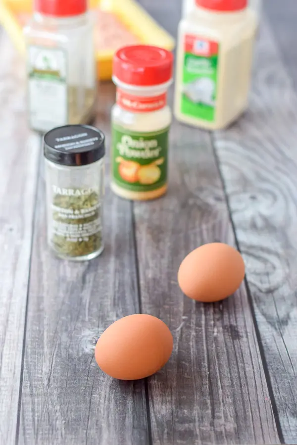 Eggs, tarragon, onion and garlic powder and chicken on a grey table