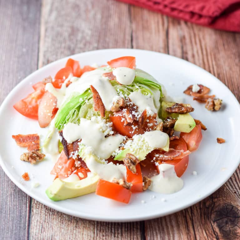 Dressing on the salad that's on a white plate with a napkin and fork in the background