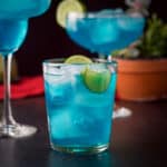 vertical view of the three glasses of the blue drink with a plant in the background - square