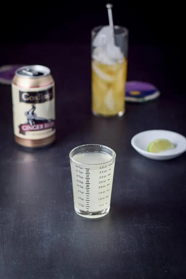 Ginger beer measured with the can, lime wedge and filling glass in the background
