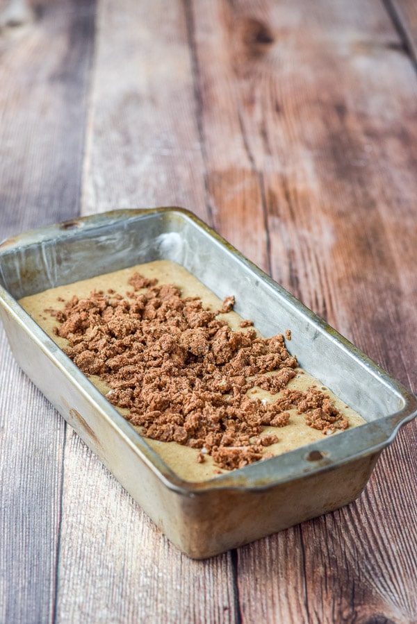 The batter in a bread pan with cinnamon crumbles on top