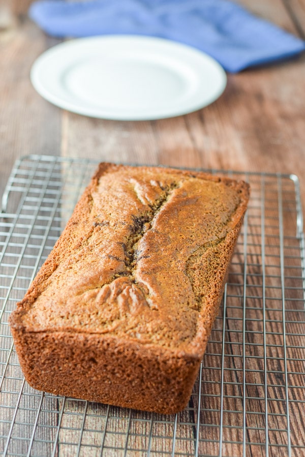 Bread cooling on a wire rack with a white plate in the background