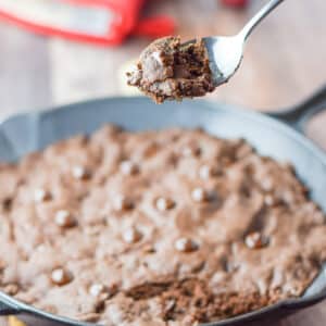 A spoonful of brownie held above the skillet - square