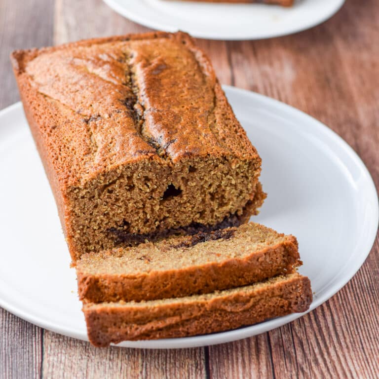 Slices of bread on a plate along with the rest of the loaf - square