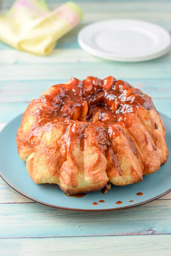 The monkey bread on a blue platter with butterscotch drizzled over it