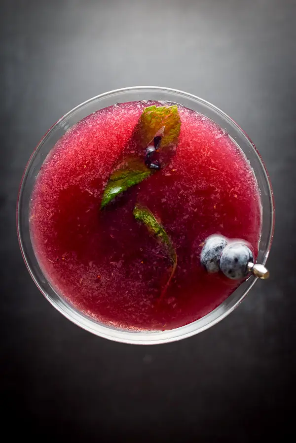 Aerial view of the blueberry cosmo with blueberries and mint leaves for garnish