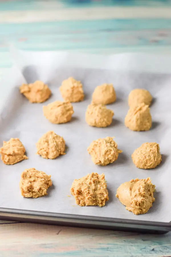 The peanut butter balls formed on a parchment paper pan