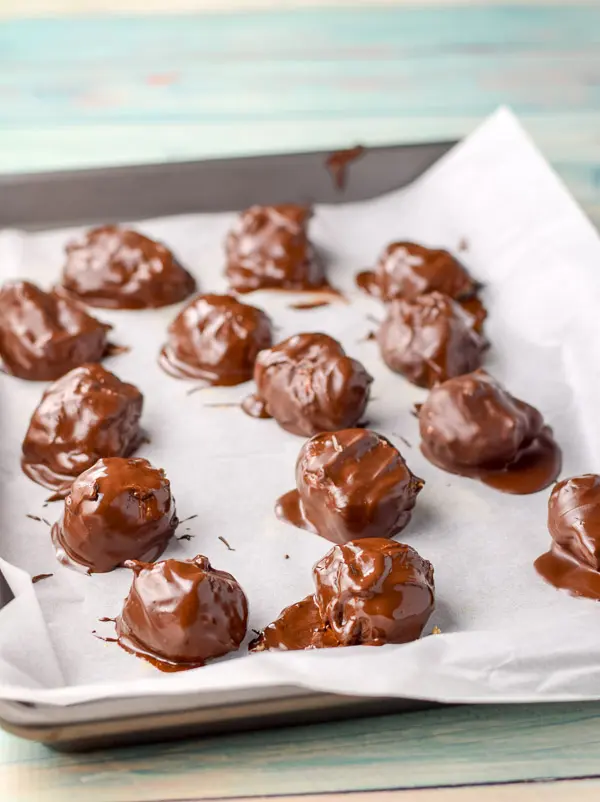 The balls dipped in the chocolate and placed on the parchment paper pan