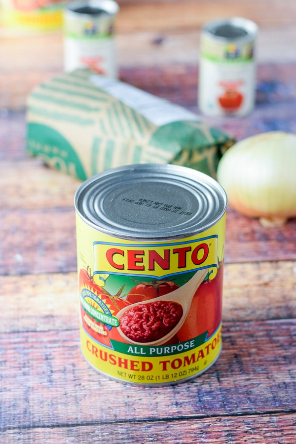 Crushed tomatoes, onion, tomato paste and ground beef on a table