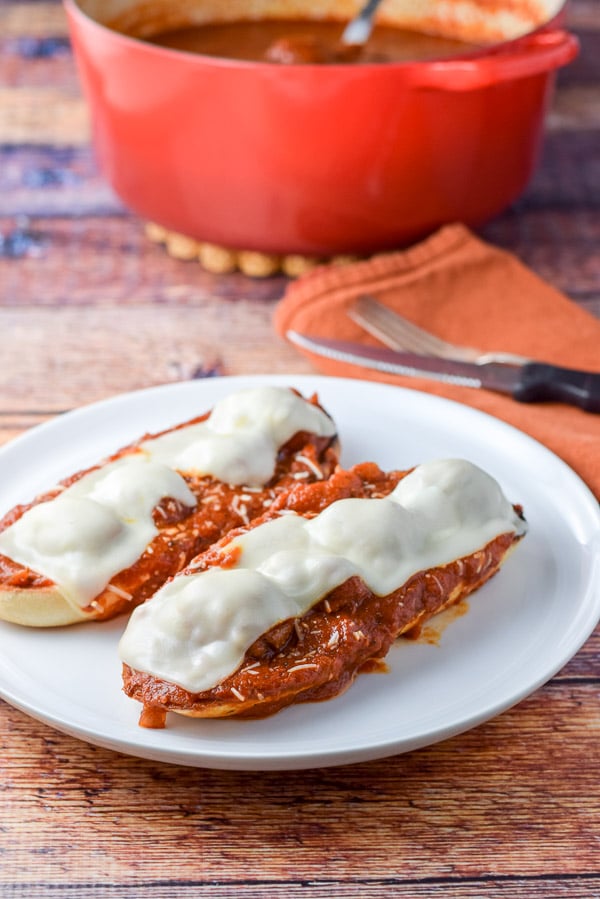 A white plate with melted cheese on the meat ball sub