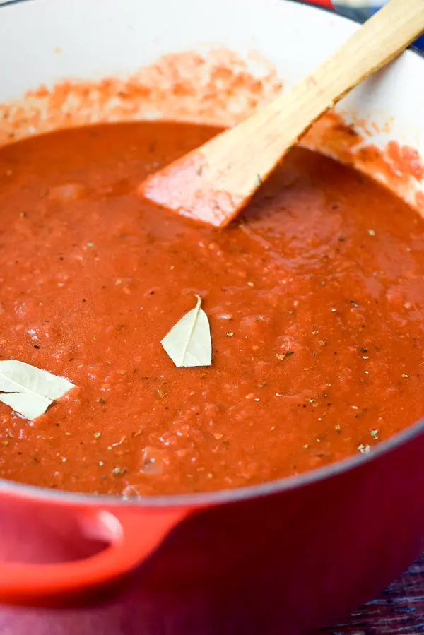 Red sauce with a bay leaf in a red Dutch oven