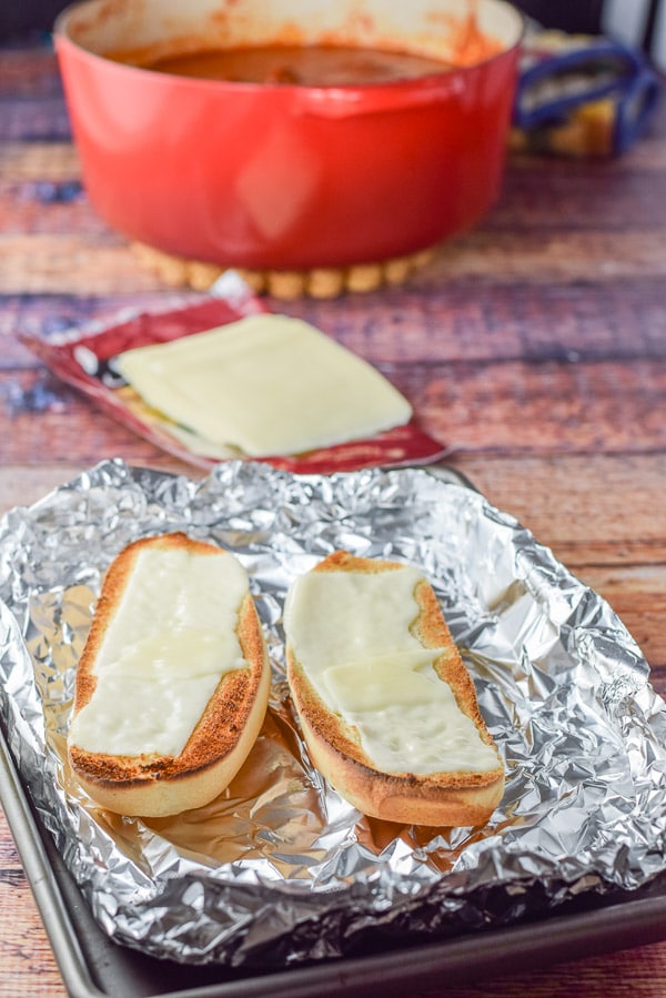 Cheese melted on bread with more cheese and sauce in the background
