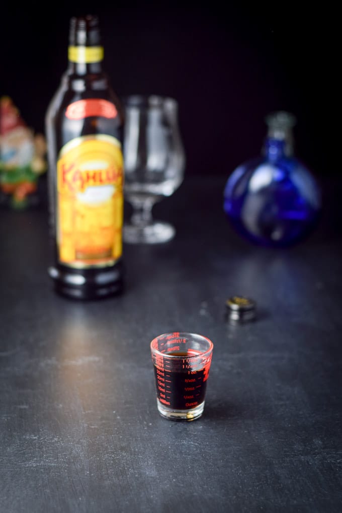 Kahlua poured out with the bottle and glasses in the background